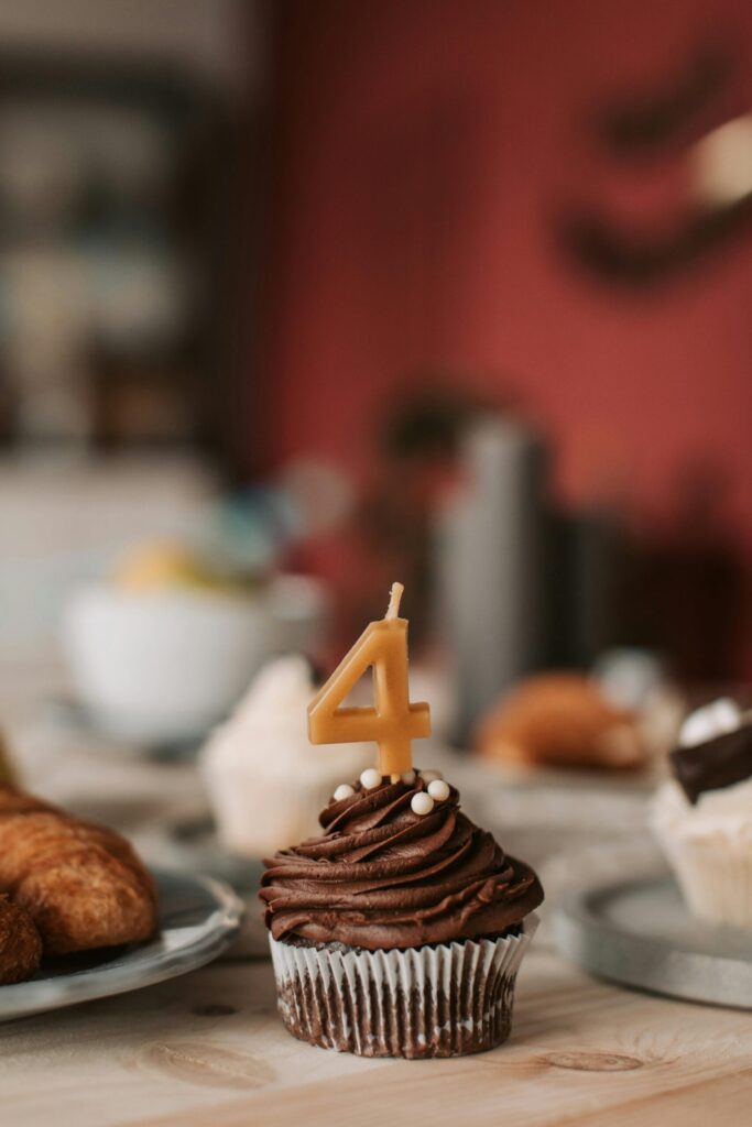 Number 4 candle on top of a chocolate cupcake.