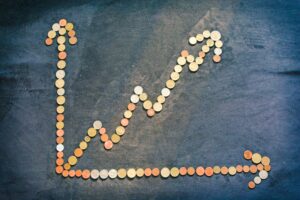 Graph made out of coins with an arrow as the axis, and an upward trend arrow.